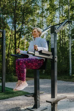 En kvinna tränar mage på ett utegym under sommaren från Omnigym