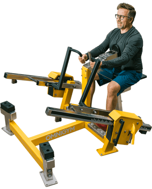 Mies hymyilee samalla, kun hän tekee soutulaite istuen harjoitusta Omnigym ulkokuntosalilla.